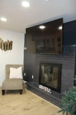 a living room with a fireplace with a tv and a chair at Spacious New4BR 3BA 2kit GameRm Firepit Amenity in Tobyhanna