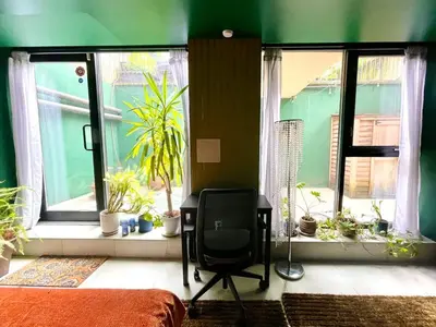 a green room with a chair and windows with plants at Bright 2-Story Brooklyn Oasis w Patio & Fire Pit in Brooklyn