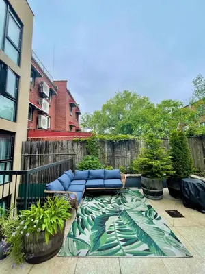 a patio with blue couches and plants and a fence at Bright 2-Story Brooklyn Oasis w Patio & Fire Pit in Brooklyn