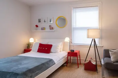 a bedroom with a bed with a red pillow and a chair at Superior Queen Bed & Fulton Bed in Mount Vernon