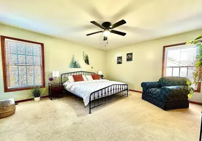 a bedroom with a bed and a fan and a chair at Charming Family Friendly House, Hot tub, Playroom in Long Pond