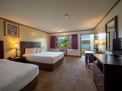 a hotel room with two beds and a flat screen tv at Lake 'N Pines Motel in Cooperstown