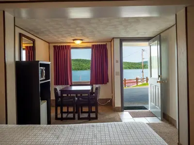 a bedroom with a table and a dining room with a view at Lake 'N Pines Motel in Cooperstown