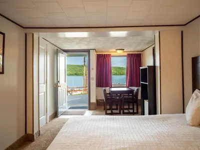 a hotel room with a bed and a table and chairs at Lake 'N Pines Motel in Cooperstown