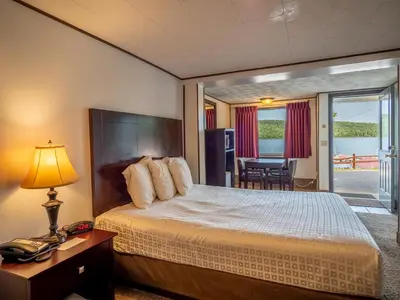 a bedroom with a bed and a table with a telephone at Lake 'N Pines Motel in Cooperstown