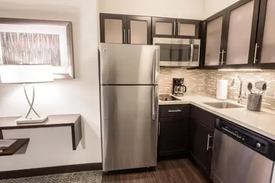 a kitchen with a stainless steel refrigerator and a lamp at Staybridge Suites Albany Wolf Rd-Colonie Center by IHG in Albany