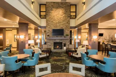 a lobby with tables and chairs and a fireplace at Staybridge Suites Albany Wolf Rd-Colonie Center by IHG in Albany