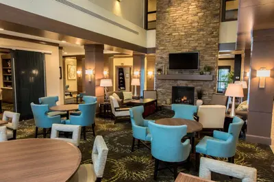 a lobby with tables and chairs and a fireplace at Staybridge Suites Albany Wolf Rd-Colonie Center by IHG in Albany