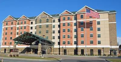 a large building with an american flag in front of it at Staybridge Suites Albany Wolf Rd-Colonie Center by IHG in Albany