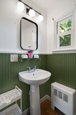a green and white bathroom with a sink and a mirror at Birches Motel in Saratoga Springs