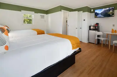 a bedroom with two beds and a table and a kitchen at Birches Motel in Saratoga Springs