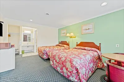 a hotel room with two beds and a table at Top Hill Motel in Saratoga Springs