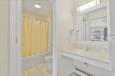 a bathroom with a sink and a toilet and a mirror at Top Hill Motel in Saratoga Springs