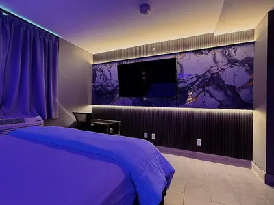 a bedroom with a bed and a tv on a wall at Umbrella Hotel Bronx in Bronx