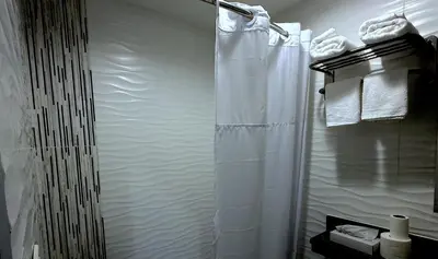 a bathroom with a shower with white towels at Umbrella Hotel Bronx in Bronx
