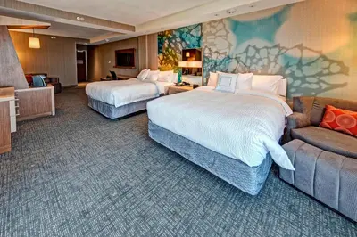 a hotel room with two beds and a couch at Courtyard by Marriott Westbury Long Island in Westbury