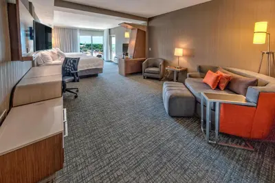 a hotel room with a couch and a bed at Courtyard by Marriott Westbury Long Island in Westbury