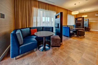 a living room with a blue couch and a table at Courtyard by Marriott Westbury Long Island in Westbury
