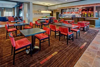 a restaurant with tables and chairs and a bar at Courtyard by Marriott Westbury Long Island in Westbury
