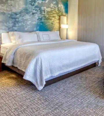 a large bed in a room with a painting at Courtyard by Marriott Westbury Long Island in Westbury