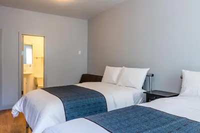 two beds in a room with white walls at The Park Ave North in New York