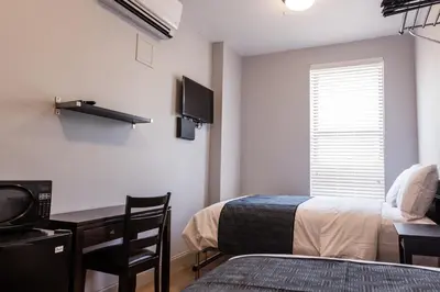 a bedroom with a bed and a desk and a tv at The Park Ave North in New York