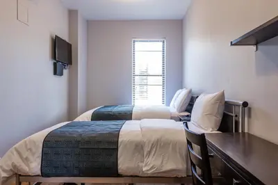 a bedroom with two beds and a desk and a window at The Park Ave North in New York