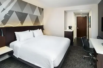 a hotel room with a large white bed and a desk at Courtyard by Marriott Long Island City/New York Manhattan View in Queens