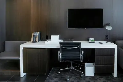 a white desk with a chair and a tv on a wall at Courtyard by Marriott Long Island City/New York Manhattan View in Queens