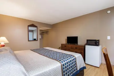 a bedroom with a bed and a tv and a refrigerator at Knights Inn Amsterdam in Amsterdam