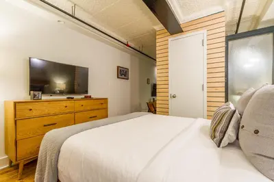 a bedroom with a bed and a dresser with a television at Franklin Guesthouse in Brooklyn