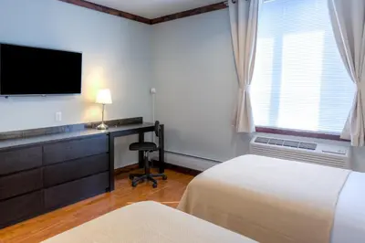 a bedroom with a desk with a television and a bed at LIC Hotel in Queens