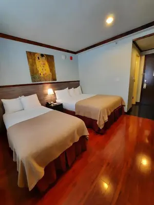 two beds in a hotel room with wood floors at LIC Hotel in Queens