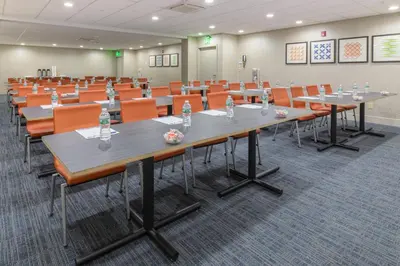 a conference room with tables and orange chairs at Holiday Inn Express Southington by IHG in Southington