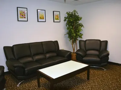 a waiting room with a leather couch and a table at Baymont by Wyndham East Windsor Bradley Airport in East Windsor