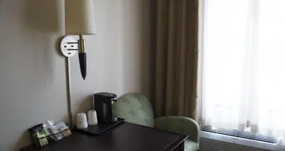 a hotel room with a desk and a chair and a lamp at Baymont by Wyndham East Windsor Bradley Airport in East Windsor