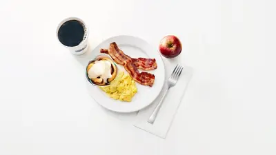 a plate of breakfast food with bacon and eggs and a cup of coffee at Holiday Inn Express Fishkill-Mid Hudson Valley by IHG in Fishkill