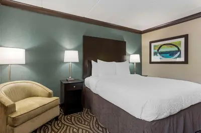 a hotel room with a large bed and a chair at Best Western Plus Kingston Hotel and Conference Center in Kingston