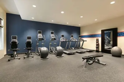 a gym with a row of exercise bikes and weights at Hampton Inn New York - LaGuardia Airport in Queens