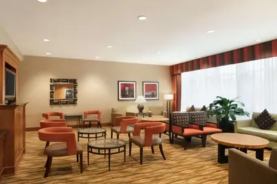 a waiting room with orange chairs and tables at Hampton Inn New York - LaGuardia Airport in Queens