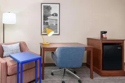 a room with a desk and a chair and a lamp at Hampton Inn Springfield South Enfield in Enfield