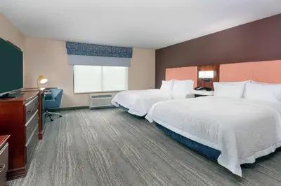 a hotel room with two beds and a television at Hampton Inn Springfield South Enfield in Enfield