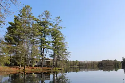 a house on a island in the middle of a lake at Alpine Lake Lakefront Park Model 4 in South Corinth