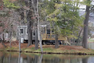 a house on the shore of a body of water at Alpine Lake Lakefront Park Model 4 in South Corinth
