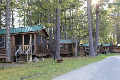 a group of log cabins in the woods at Alpine Lake Lakefront Cabin 5 in South Corinth