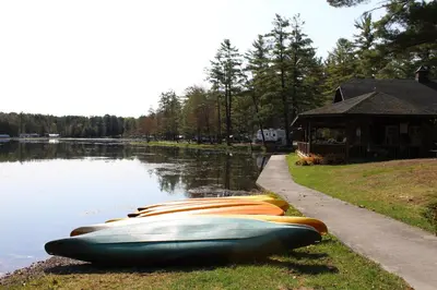 a row of boats sitting on the side of a lake at Alpine Lake Lakefront Cabin 5 in South Corinth