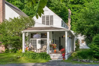 a white house with flowers on the front porch at Inn at Silver Maple Farm in East Chatham