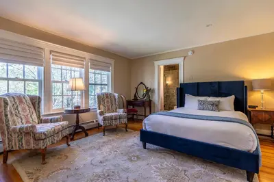 a bedroom with a large bed and two chairs at The White House Inn in Wilmington