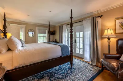 a bedroom with a bed and a chair and windows at The White House Inn in Wilmington