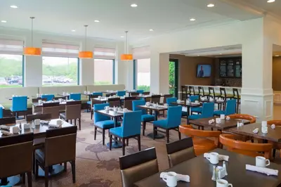 a dining room with tables and blue chairs at Hilton Garden Inn Hartford South/Glastonbury in Glastonbury